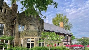A stone building with a corner entrance, surrounded by well-maintained hedges and a pathway. - Salt Run Retreat| Trails, Decks, & Screened Porch (Granville)
