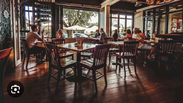 A restaurant with wooden floors and tables, large windows, and a chandelier. - Salt Run Retreat| Trails, Decks, & Screened Porch (Granville)