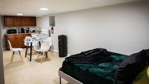 Une pièce de taille modeste comprenant un lit, un coin cuisine et un espace repas.