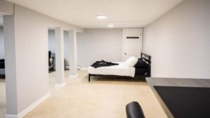 Une chambre avec un lit, un bureau et une chaise. Il y a une porte et une fenêtre dans la pièce.