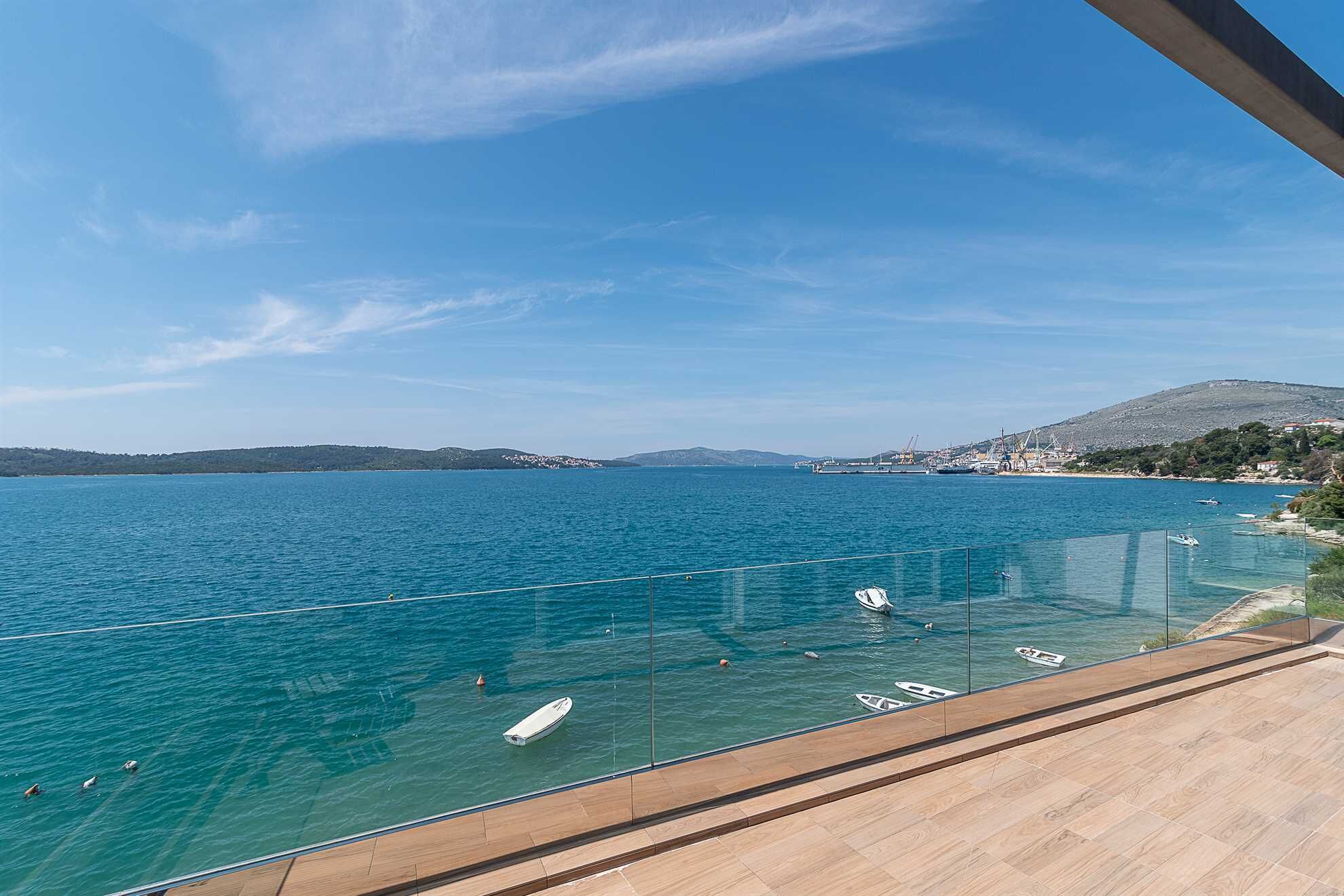 A clear view of a large body of water with boats, a distant shoreline, and a hilly landscape.