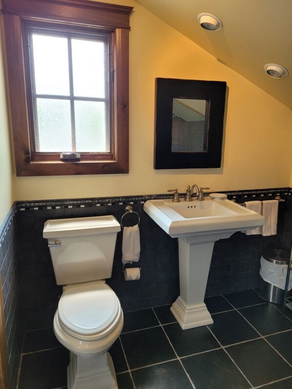 A bathroom with a toilet, sink, and window.