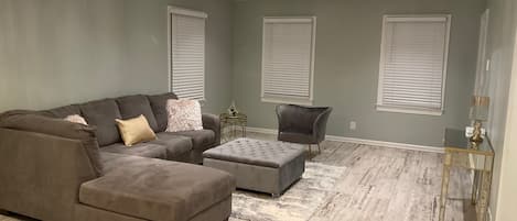 Una sala de estar con sofá modular, reposapiés y un sillón.