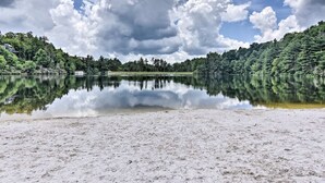 Ein Strand mit einem ruhigen See, der Himmel und Bäume spiegelt.