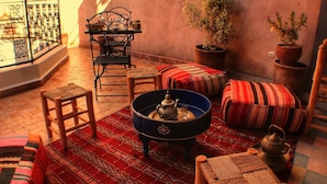 A cozy interior with a patterned rug, a blue coffee table with a teapot, and a metal chair.