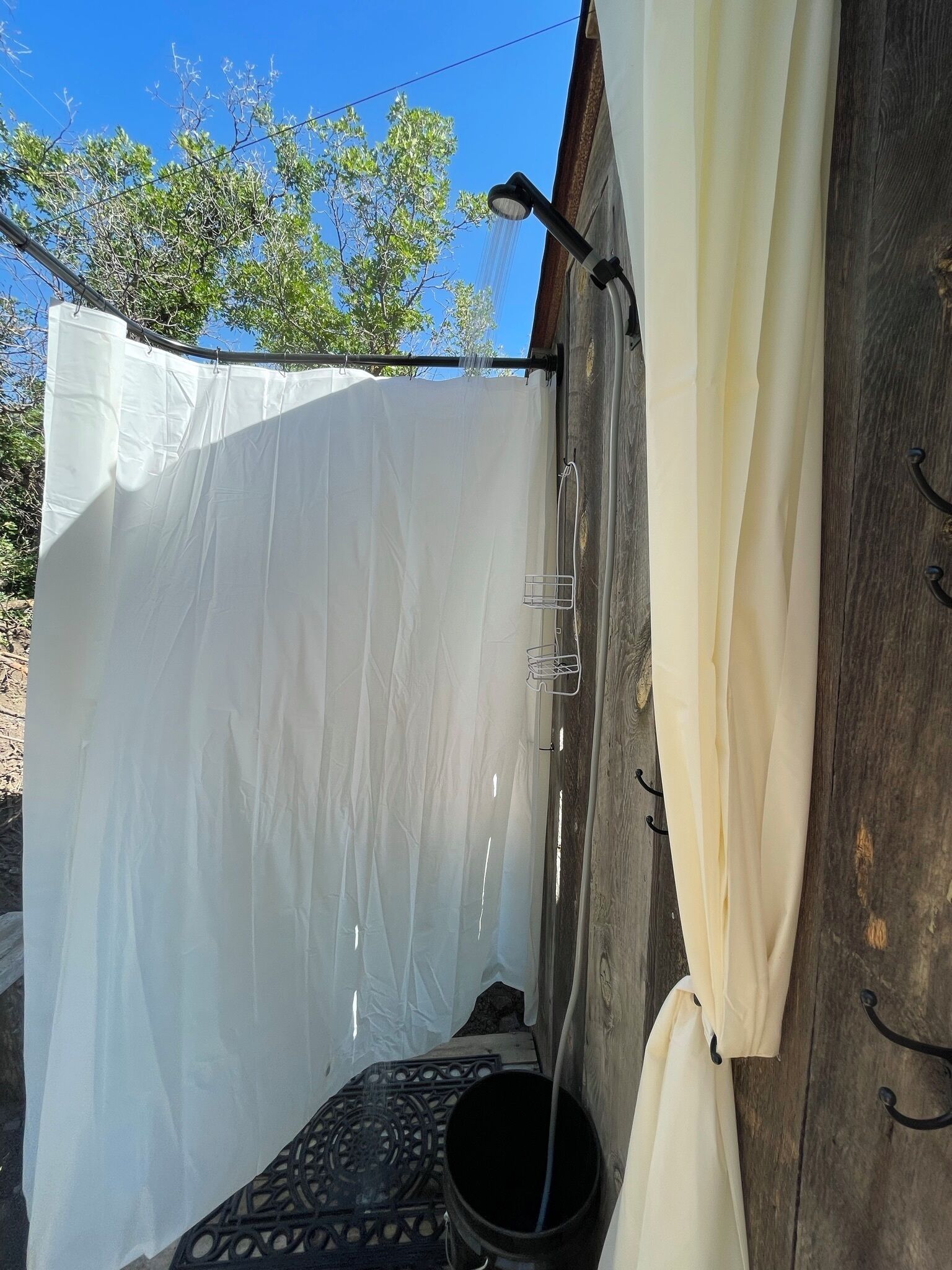A tent with a white interior, a black bucket, and a metal rack.