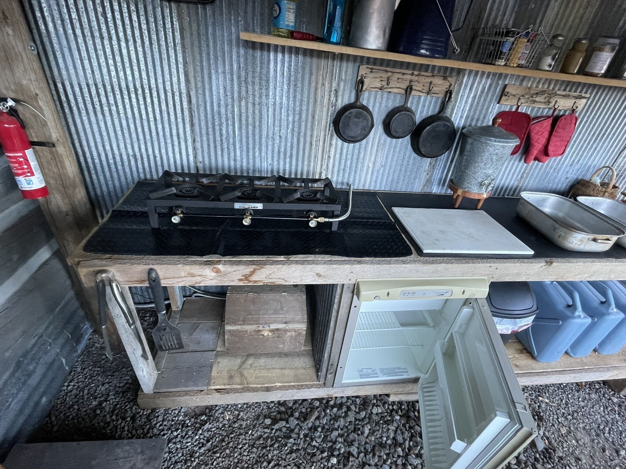 A compact kitchen with a gas stove, a sink, and various utensils.