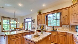 A spacious kitchen with wooden cabinets, a large island, and ample natural light from windows. - Spacious Greenbrier Vacation Rental on ~ 4 Acres! (Greenbrier)