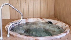 Un jacuzzi con una escalera de metal, frente a una pared de madera.