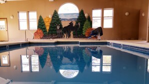 Una piscina con un mural de animales y árboles, un tragaluz y vistas al cielo.