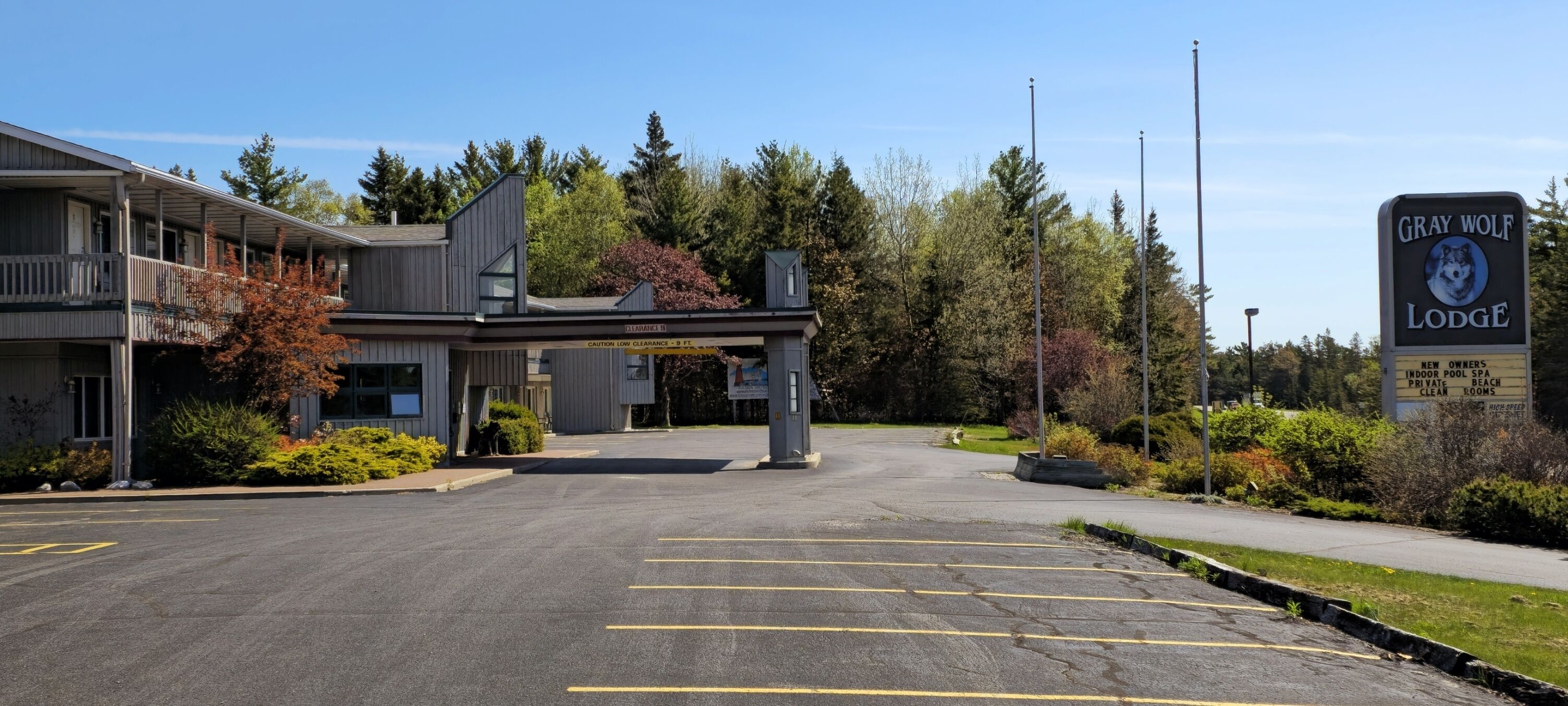 A building with a sign reading "Gray Wolf Lodge" and a parking lot in front.