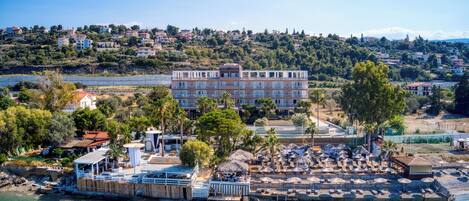 A coastal hotel with a large building, outdoor seating area, and a view of the sea.