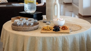 A round table with a white tablecloth, a white vase with dried pampas grass, a glass jar with a drink, and a bowl of snacks. - Black and White Boho Resort (Xylokastro-Evrostina)