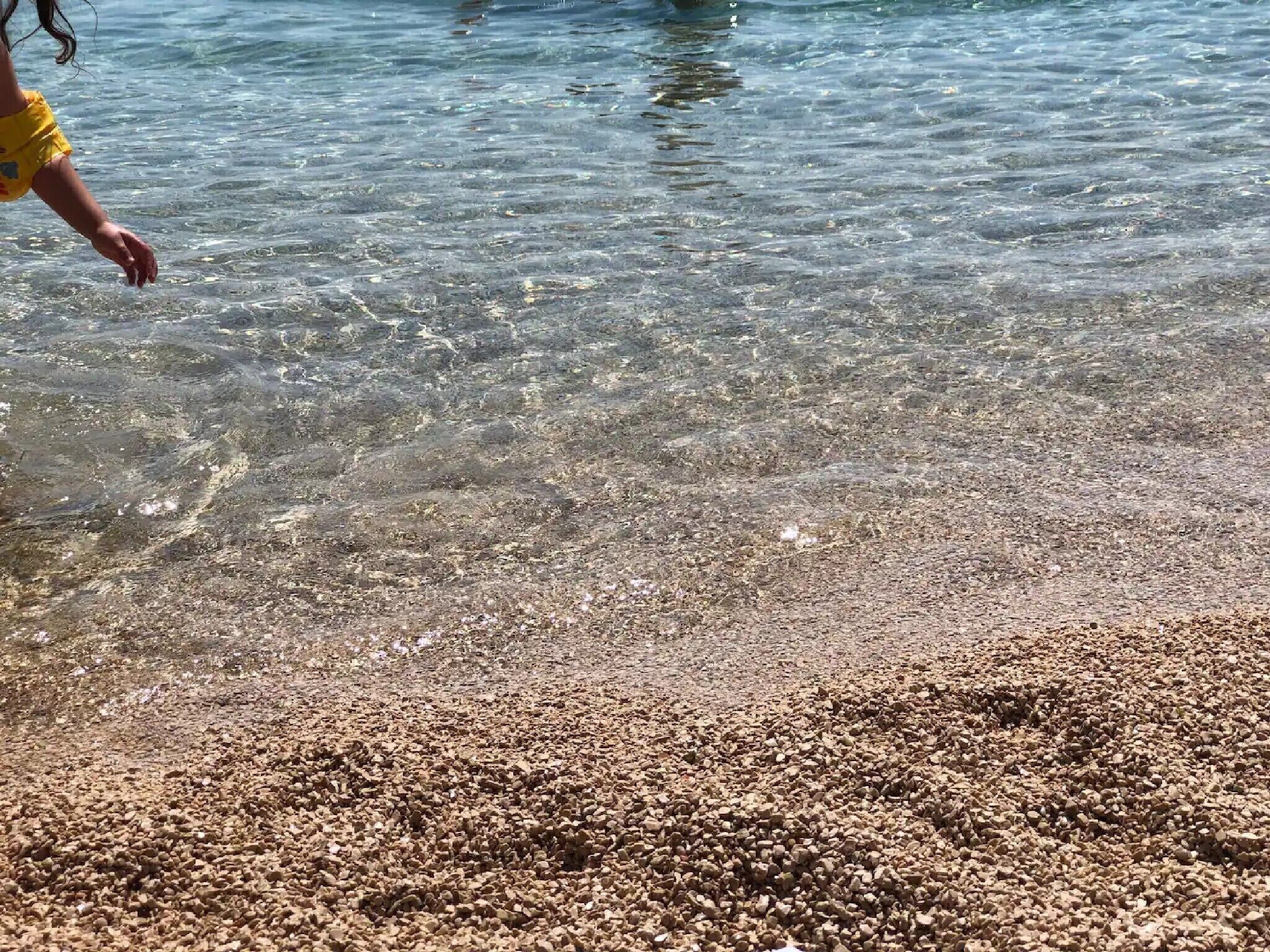 Een kiezelstrand met helder water.