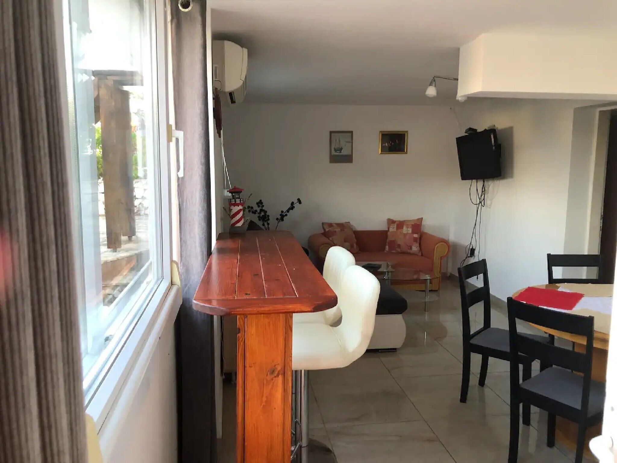 Een woonkamer met een bank, een houten tafel en een aan de muur bevestigde televisie.