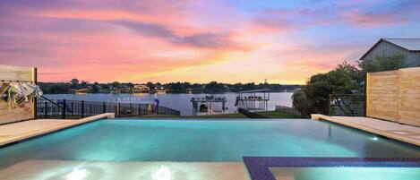 A swimming pool with a view of a body of water and a dock in the background.