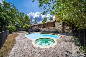 Relax by the serene pool surrounded by lush greenery and trees.