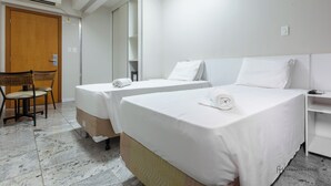 Ett hotellrum med två separata sängar, en trädörr, en stol och en vit garderob.