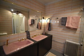 Une salle de bain avec deux lavabos, un miroir, des porte-serviettes et un radiateur.