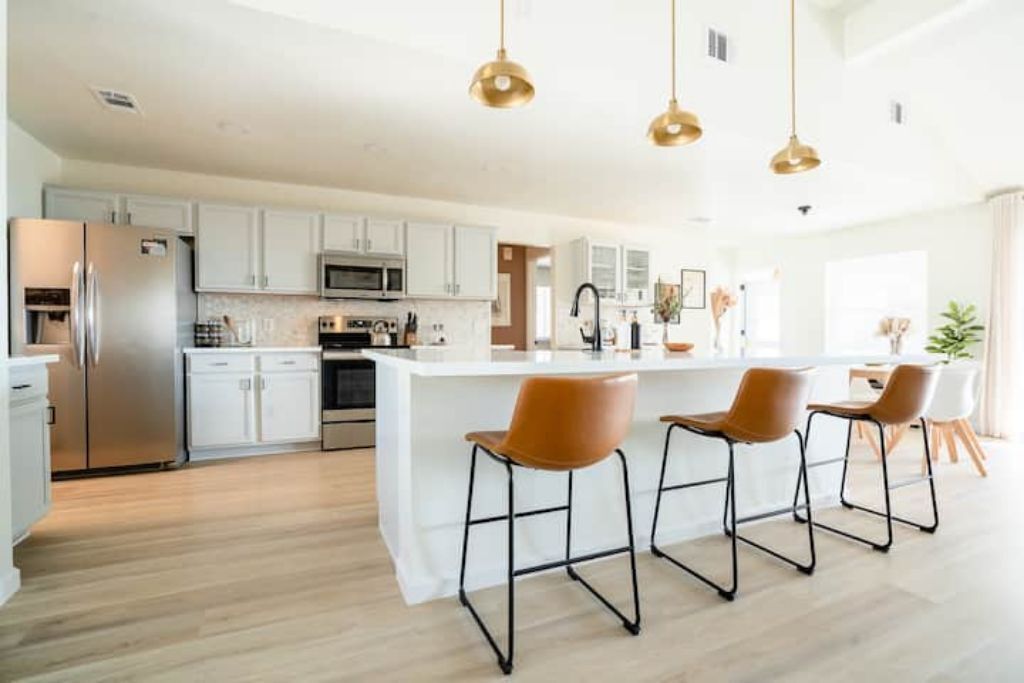 A modern kitchen with white cabinets, stainless steel appliances, and a central island with bar stools.
