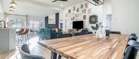 A modern dining area with a wooden table, black chairs, and a ceiling fan.