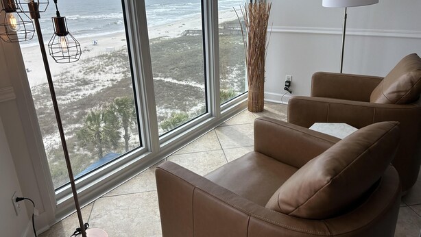 Een moderne woonkamer met een groot raam met uitzicht op het strand en de oceaan.