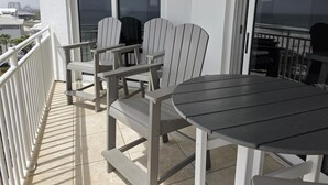 Een balkon met een tafel en stoelen, een leuning en uitzicht op de stad.