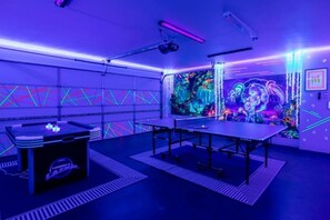 A room with a table, chairs, a projector, and a colorful mural.