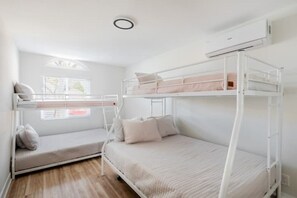 Ein Schlafzimmer mit Etagenbetten, einem Fenster, einem Deckenventilator und einer Klimaanlage.
