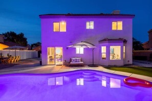 Ein zweistöckiges Haus mit Swimmingpool, Sitzgelegenheit im Freien und einer Terrassenfläche.