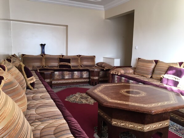 A living room with a sectional sofa, a round coffee table, and patterned rugs.
