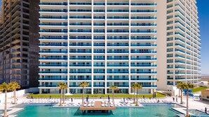 A high-rise hotel with a large pool area, multiple balconies, and palm trees. - Encantame Towers (Puerto Peñasco)
