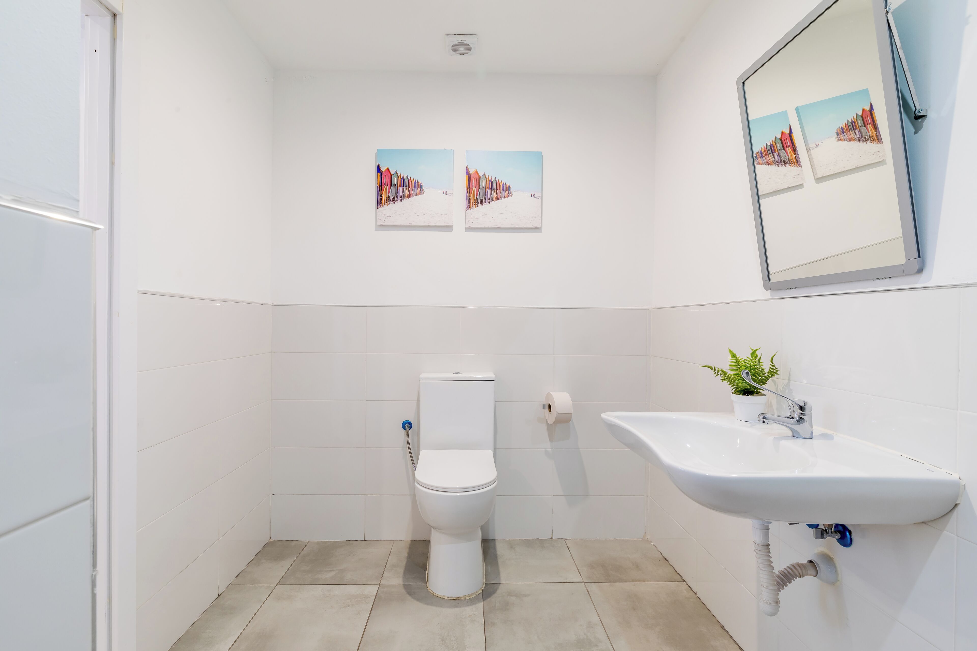 Un baño con inodoro, lavabo y dos cuadros en la pared.