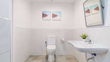 Un baño con inodoro, lavabo y dos cuadros en la pared.