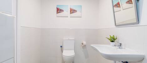 Une salle de bain avec des toilettes, un lavabo et deux tableaux encadrés accrochés au mur.