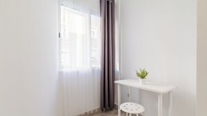 A small, bright room with a white table and a single chair, a potted plant on the table, and a window with sheer curtains. - LooP Las Ventas - Adults Only (Madrid)