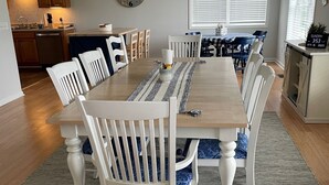 Ruokailutila, jossa on puinen pöytä, valkoiset tuolit ja kuviollinen matto.
