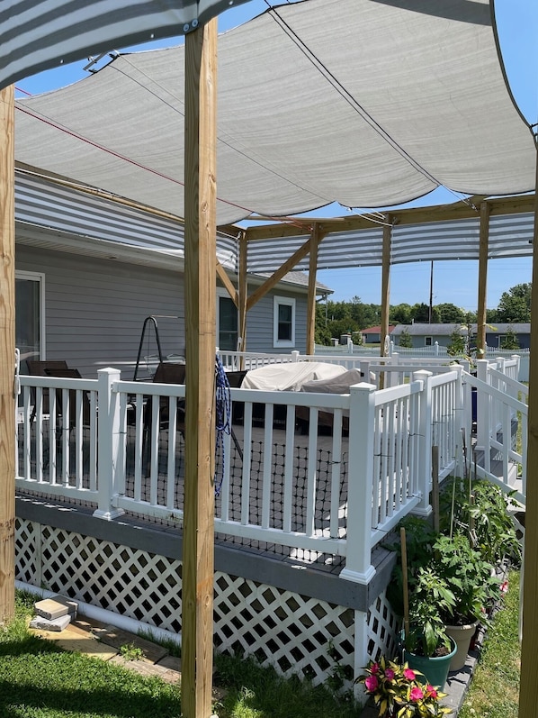 A covered patio area with a white railing, wooden posts, and a lattice fence.