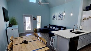 A modern kitchen with a wooden dining table, a built-in island with a sink, and a ceiling fan. - Hightide Hideaway Beach Getaway. (Corpus Christi)