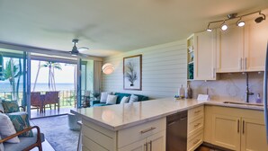 A modern kitchen with a large island, white cabinetry, and a view of the ocean. - Oceanfront, Hale Kai O Kihei, incredible sunsets, King bed, AC, remodeled 2023 (Kihei)