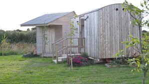 Une cabane en bois avec un toit en métal, un escalier en bois et un petit porche.