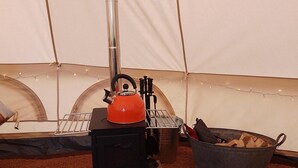 Un réchaud portable avec une bouilloire, un seau en métal rempli de bois et une cheminée.