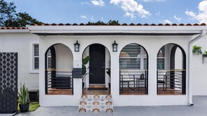 A white building with a tiled entrance, three arched windows, and a black door.