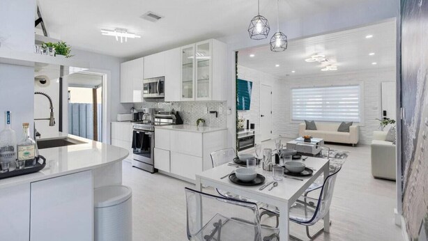 A modern kitchen with white cabinetry, a central island, and pendant lighting.