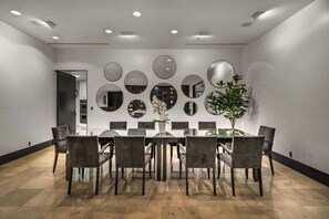 Een moderne eetruimte met een lange tafel, meerdere stoelen en een wand versierd met ronde spiegels.