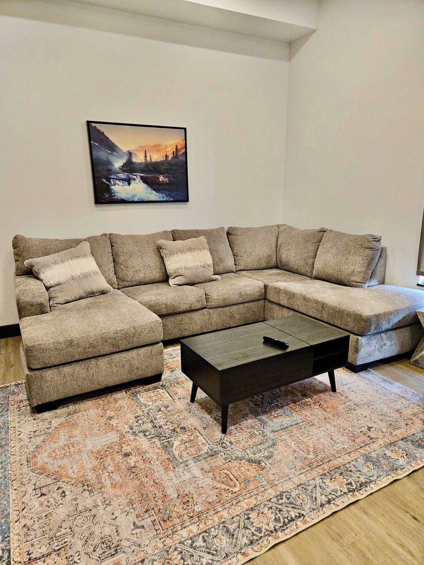 A living room with a sectional sofa, a coffee table, and a patterned rug.