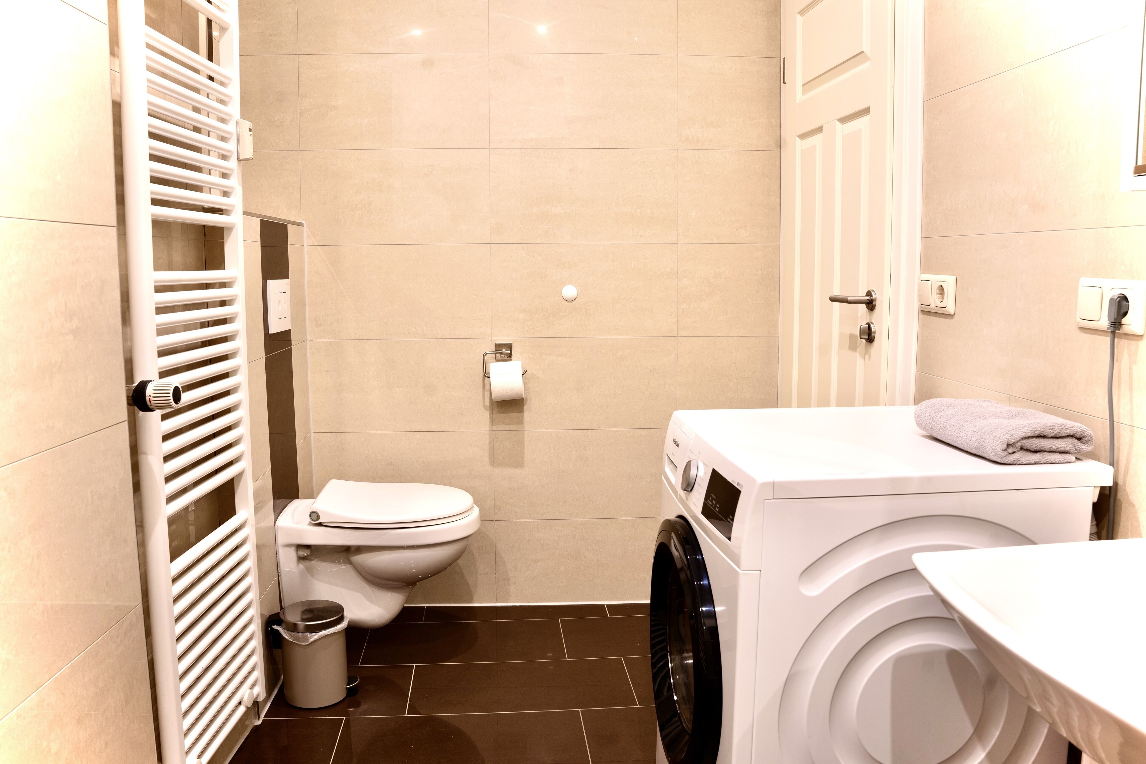 Un baño pequeño con inodoro, lavadora y radiador.