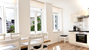 A modern kitchen with white cabinetry, a wooden dining table, and chairs. - Wunderschöne Ferienwohnung Inmitten der Altstadt (Schwerin)
