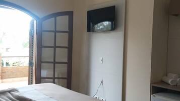 Quarto de hotel com duas camas, televisão na parede, um pequeno frigorífico e janela com vista para o exterior.