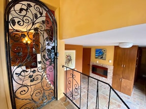 Staircase leads to an upper floor, flanked by a door and a wall with a painting.